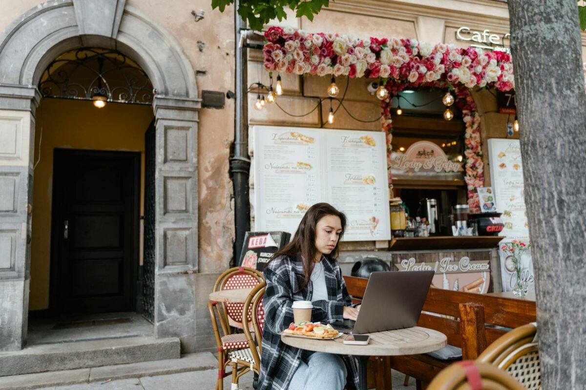 How to work remotely abroad — a woman working on a laptop at an outdoor cafe
