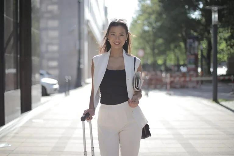 Asian woman moving abroad with suitcase in city