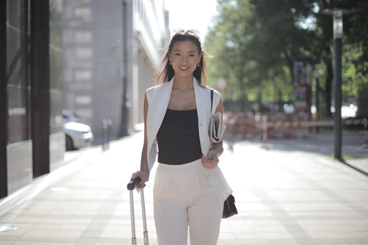 Asian woman moving abroad with suitcase in city