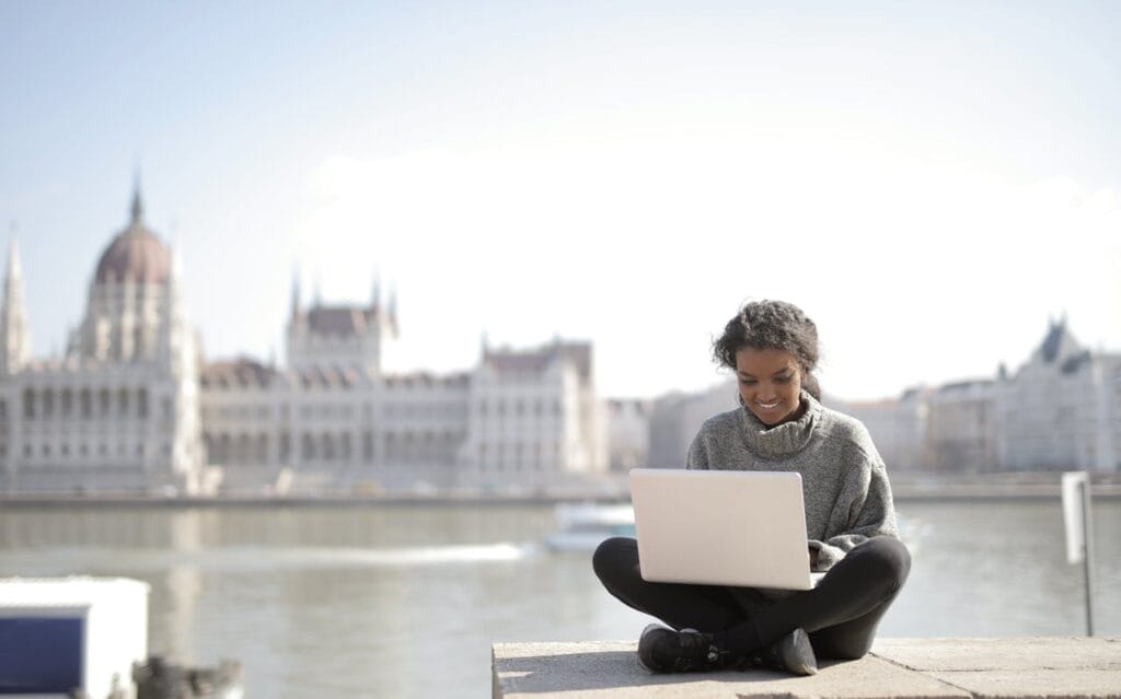 17 Proven Tips to Work Remotely While Traveling: Your Ultimate Guide 2 woman working remotely while traveling in Europe with laptop