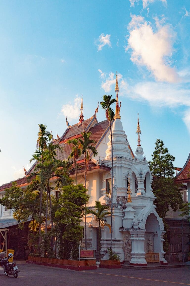 cost of living in chiang mai for americans - traditional Thai temple with golden spires and palm trees in Chiang Mai