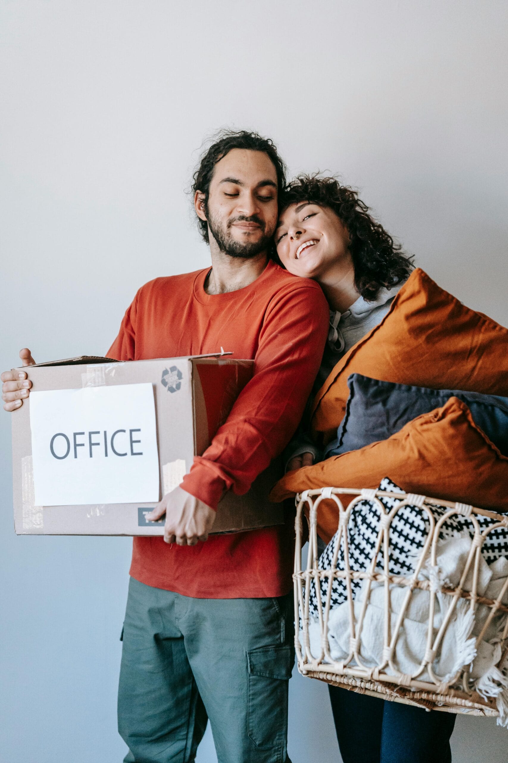 A young couple packing suitcases in a bright living room with moving boxes and travel materials about Spain.