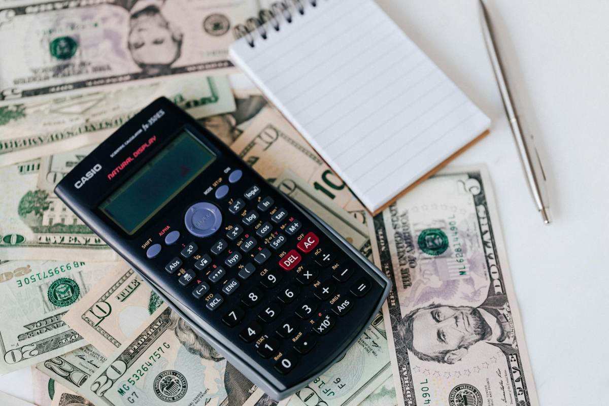 calculator and notepad on US dollars for move abroad budget planning and financial runway calculation