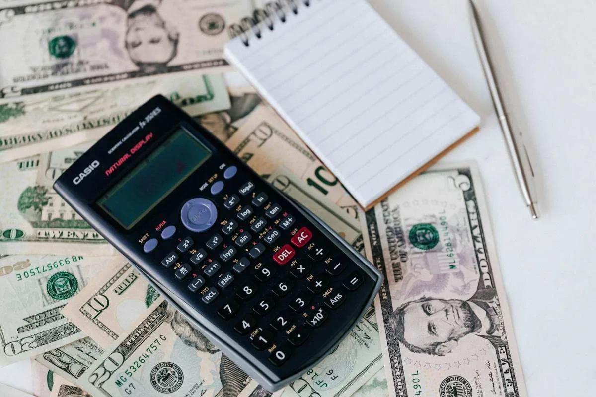 calculator and notepad on US dollars for move abroad budget planning and financial runway calculation