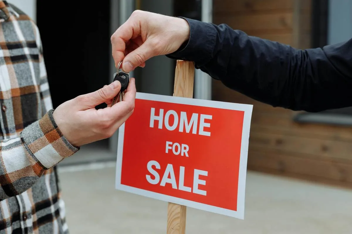 person handing house keys symbolizing selling home to fund move abroad and build financial runway