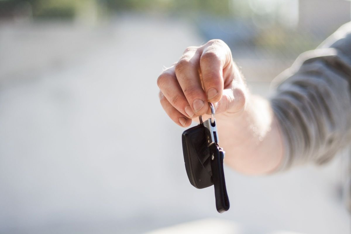 Sell Everything and Move Abroad: The 7 Real Numbers From My Move 3 Hand holding out a black car key fob against a bright blurred background