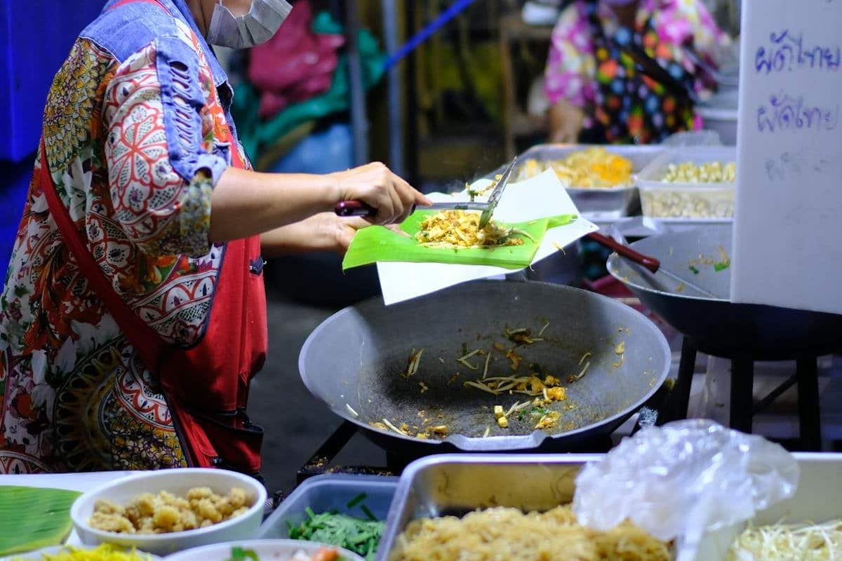 Moving to Thailand as an American: 7 Things Nobody Tells You (2026) 3 Street food vendor cooking noodles in a wok at a Thai night market