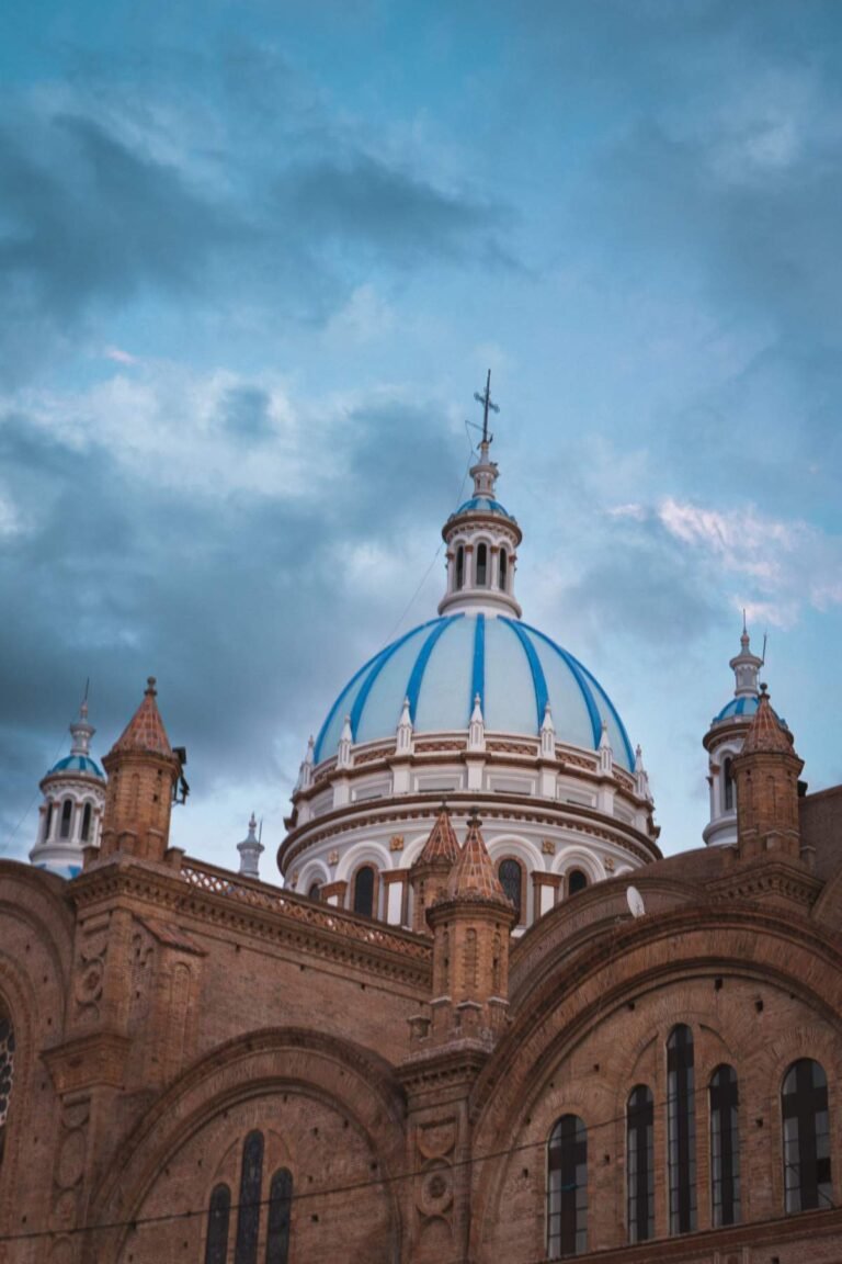 Blue tiled domes of the New Cathedral in Cuenca, Ecuador, under a cloudy sky