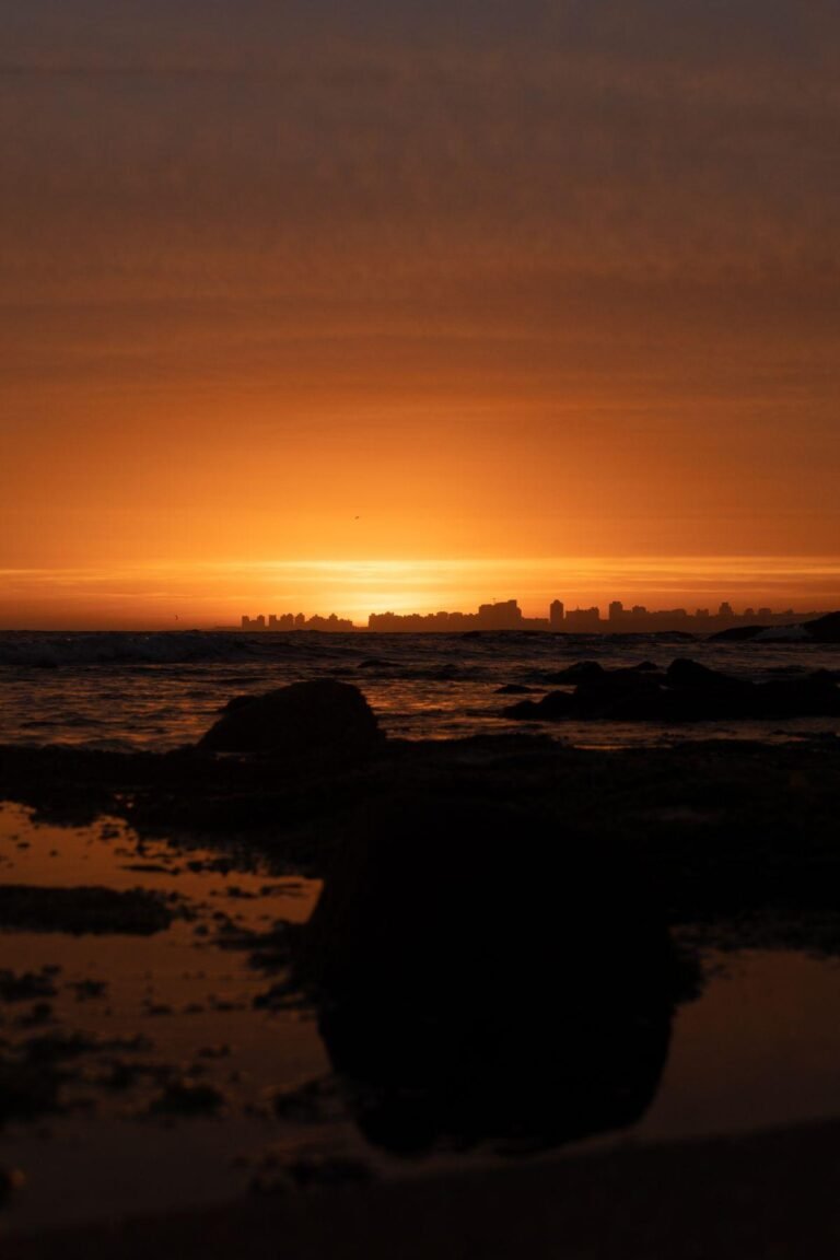 9 Safest Countries in Latin America for Americans (2026) 19 Sunset over the rocky shore at Punta del Este, Uruguay, with the city skyline in silhouette